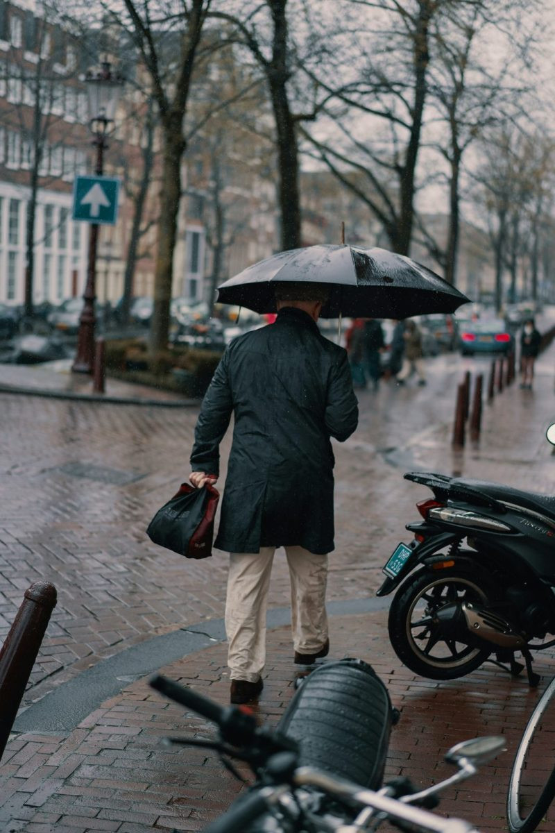 Man in a dark coat with an umbrella in fall