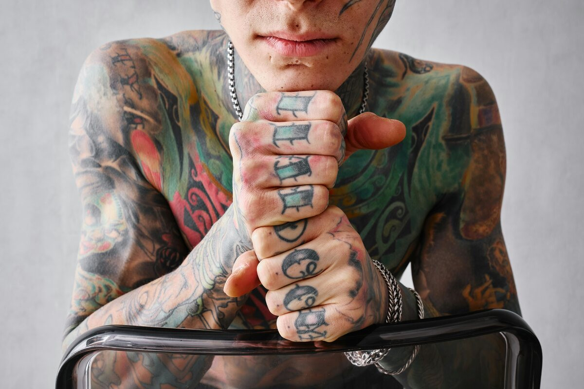 Heavily tattooed man stacking his fingers covered in small icons