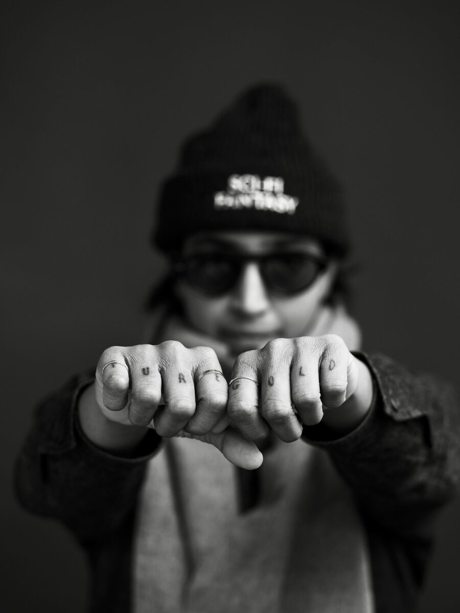 Black and white shot of fists with small knuckle tattoos held toward the camera